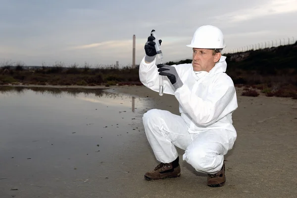 Worker in a protective suit examining pollution — Stock Photo, Image