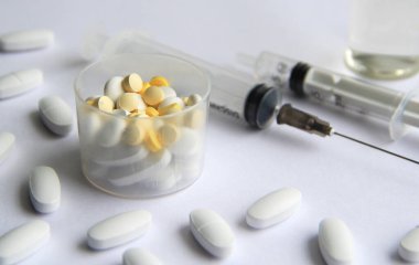 Aşılı şırıngalar ve arka planda farklı tabletler.