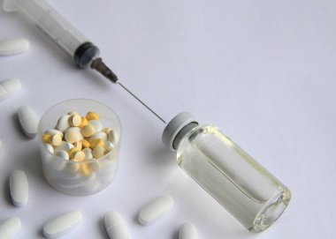 Aşılı şırıngalar ve arka planda farklı tabletler.