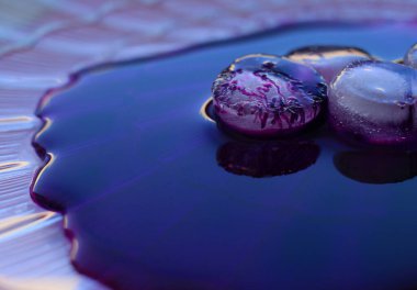 Mor arkaplan ve koyu benekli buz parçalarından oluşan soyut bir resim