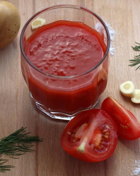 Frischer Tomatensaft im Glas mit Tomaten, Salz, Knoblauch und Kräutern auf einem Holzbrett, Draufsicht — Stockfoto