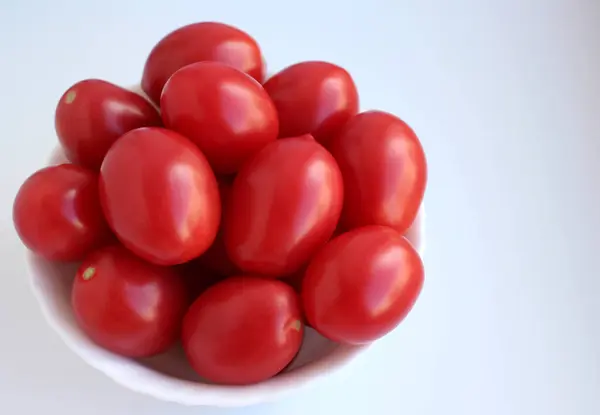 Red conical tomatoes in a cup on a white background, top view — Stock Photo, Image