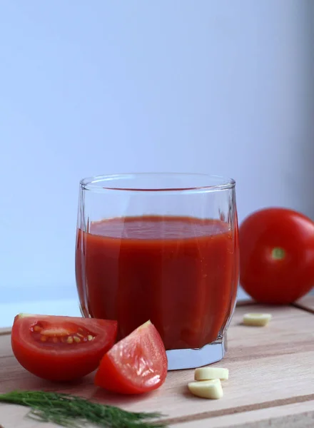 Jugo de tomate fresco en un vaso con tomates, sal, ajo y hierbas en una tabla de madera — Foto de Stock