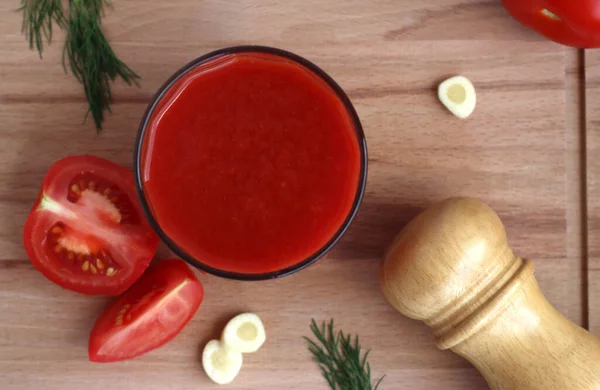 Fresh tomato juice in a glass with tomatoes, salt, garlic and herbs on a wooden board, top view — Stock Photo, Image