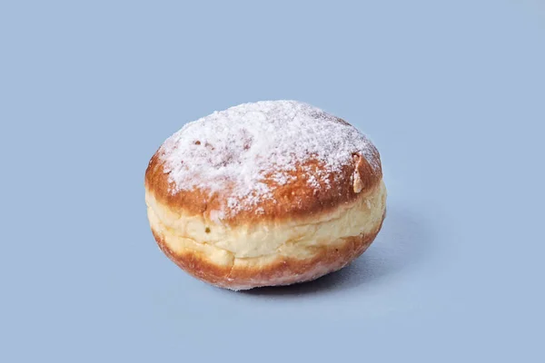 One sweet doughnut with filling. Isolated on a blue background.