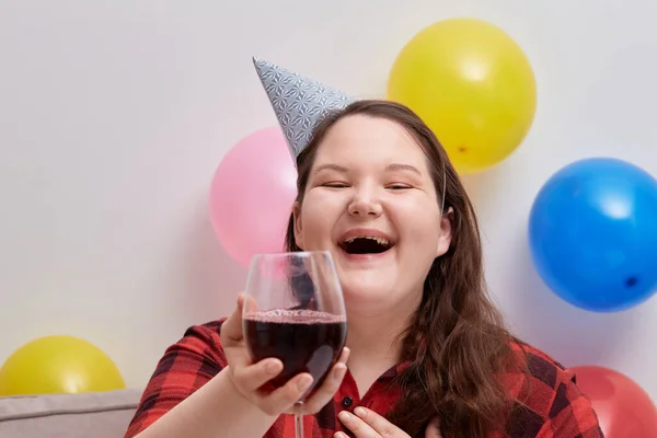 Una giovane donna felice festeggia il suo compleanno con un bicchiere di vino rosso. — Foto Stock