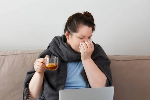 Donna malata con influenza, febbre e naso che cola, che lavora online, con un portatile. — Foto Stock