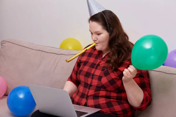 Una joven mujer celebra su cumpleaños en casa en línea con un ordenador portátil en sus manos. —  Fotos de Stock