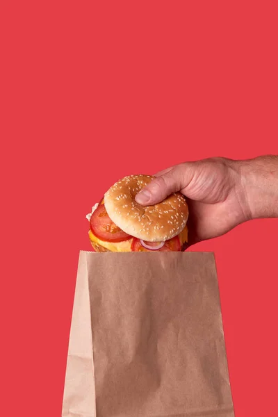 The delivery guy puts a big juicy Burger in a craft brown eco bag.