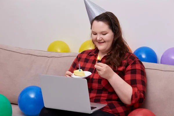 Una joven mujer celebra su cumpleaños con un pedazo de pastel de cumpleaños en sus manos —  Fotos de Stock