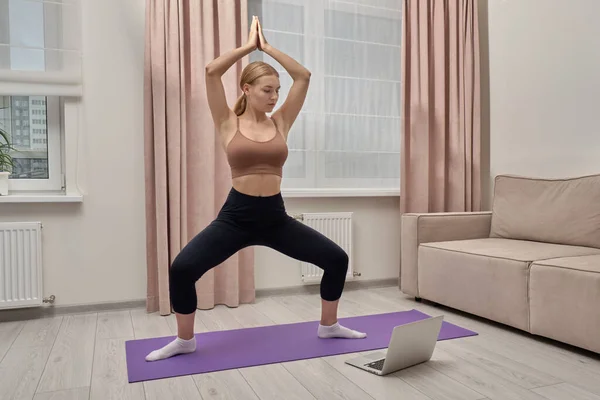 Жінка вчиться йоги в Інтернеті, дивиться на екран у ноутбуці.. — стокове фото
