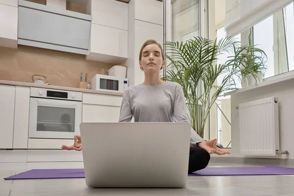 Uma jovem com olhos fechados está sentada em uma pose de ioga. Yoga formação on-line. — Fotografia de Stock