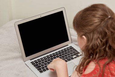 Dalgalı saçlı bir kız siyah bir dizüstü bilgisayara bakıyor. Çevrim içi eğitim.