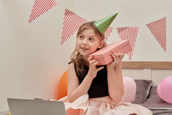 Una hermosa chica linda en un traje inteligente sostiene un regalo en una caja en su mano. —  Fotos de Stock