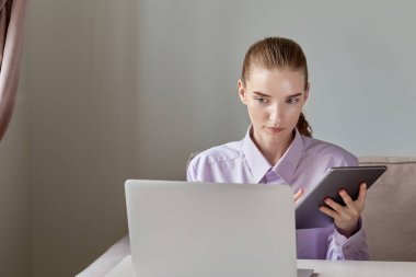 İnternette elinde tabletle çalışan bir kadın ekrana bakıyor.