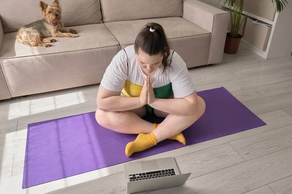 Молода жінка робить йогу, поруч з нею є ноутбук . — стокове фото