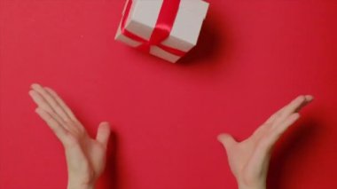 Kırmızı kazaklı bir kadının elleri Noel kutusuna hediye atıyor..