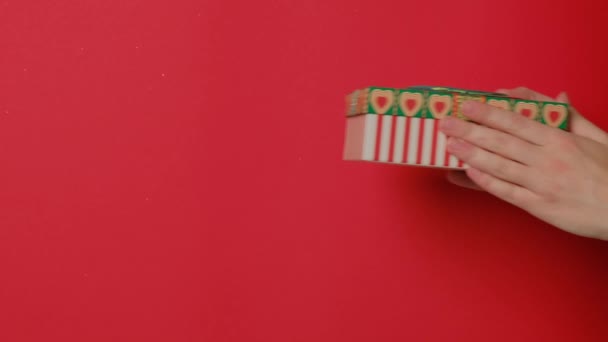 Eine Frauenhand in einem Strickpullover hält ein Geschenk in einer festlichen Glitzerbox. — Stockvideo