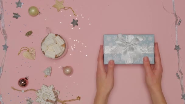 Womens hands put a festive blue box decorated with snowflakes. Flat lay. — Stock Video