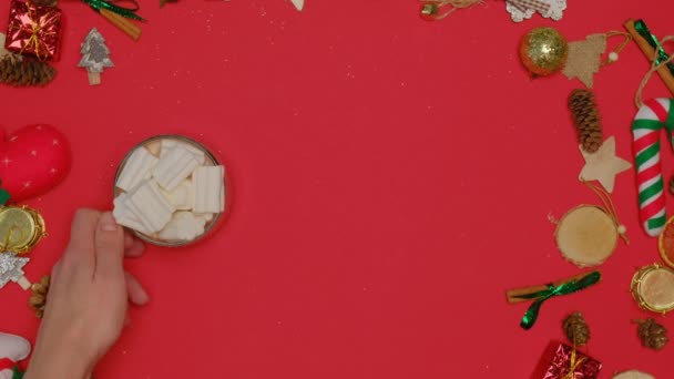 Kvinnors händer sätta en mugg varm kakao med marshmallows på en röd bakgrund. — Stockvideo