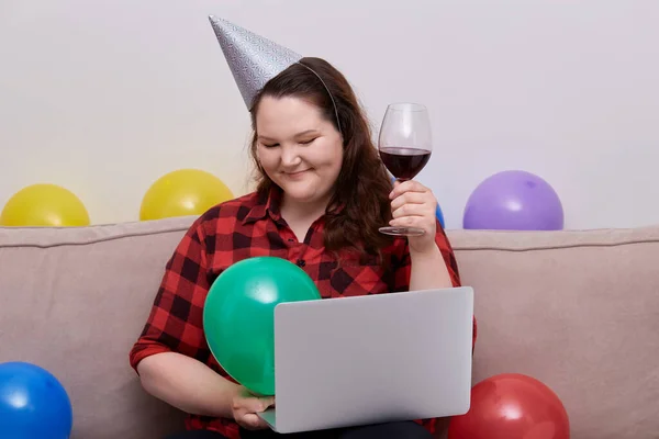 En kvinna i plus-storlek firar sin födelsedag under pandemin och dricker vin. — Stockfoto