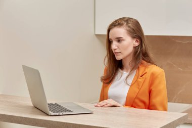 Ciddi yüzlü güzel bir genç kadın dizüstü bilgisayar ekranına bakıyor..