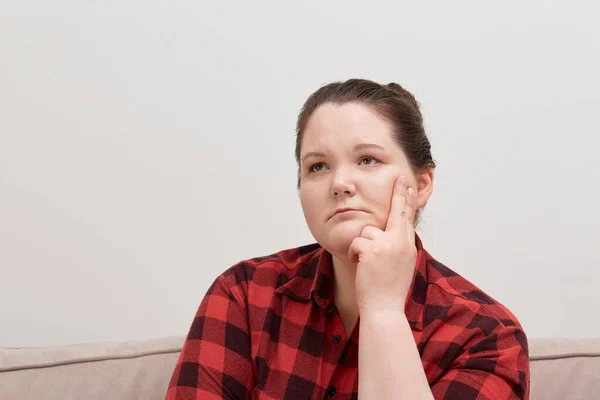 Una bella giovane donna bruna con un viso triste distoglie lo sguardo in una camicia a quadri — Foto Stock