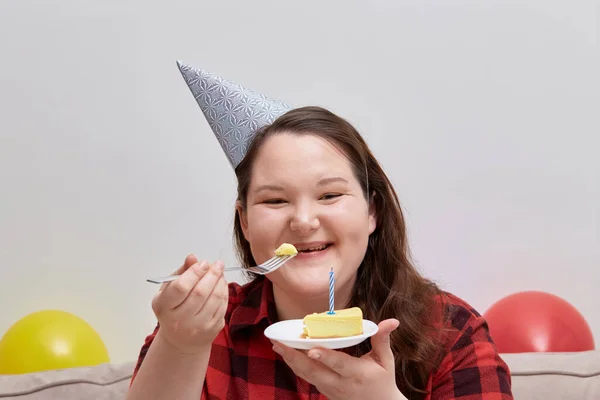 Una mujer come un pastel de cumpleaños y se ríe. Modelo de tamaño más. —  Fotos de Stock
