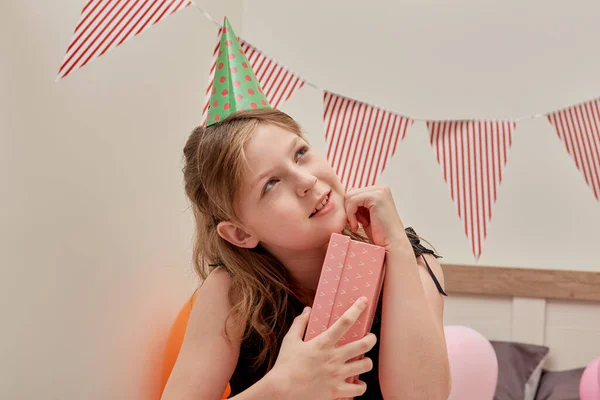 En söt flicka håller fast sin gåva i en rosa låda tätt intill kameran. — Stockfoto