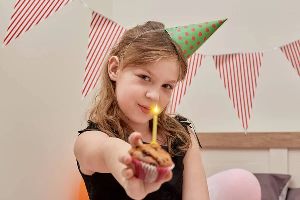 Söt flicka med en festlig cupcake i händerna, ett ljus på cupcake. — Stockfoto