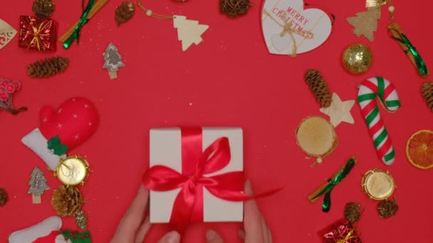 Ett platt ligg. En vacker liten gåva i en vit låda med ett rött sidenband. — Stockvideo