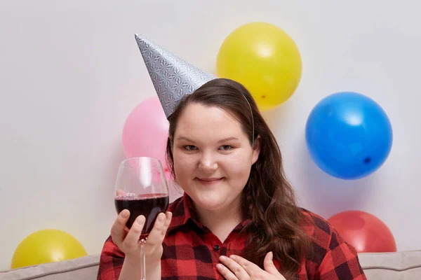 Una donna festeggia il suo compleanno con un bicchiere di vino e guarda la macchina fotografica. — Foto Stock