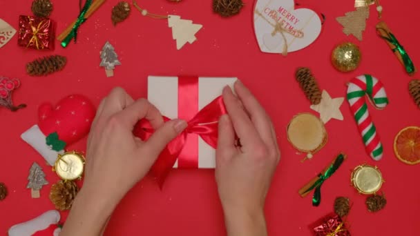 Frauenhände justieren den Bogen auf der Geschenkbox. Ein Geschenk zu Weihnachten und Neujahr. — Stockvideo