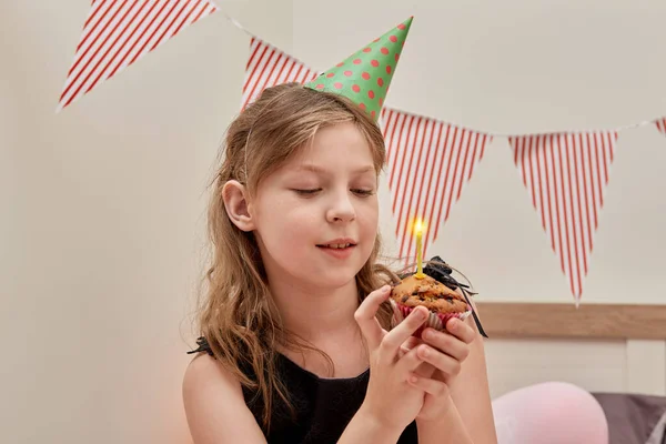 귀여운 소녀가 손에 불타는 촛불을 들고 잔치용 컵 케익을 들고 있다. — 스톡 사진