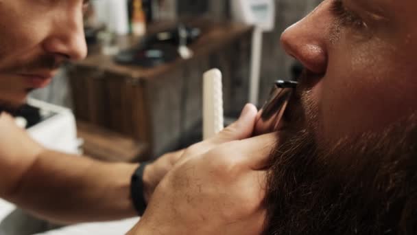 Peluquero corta el bigote de los clientes con un cortador, cuidado de la barba profesional. — Vídeos de Stock