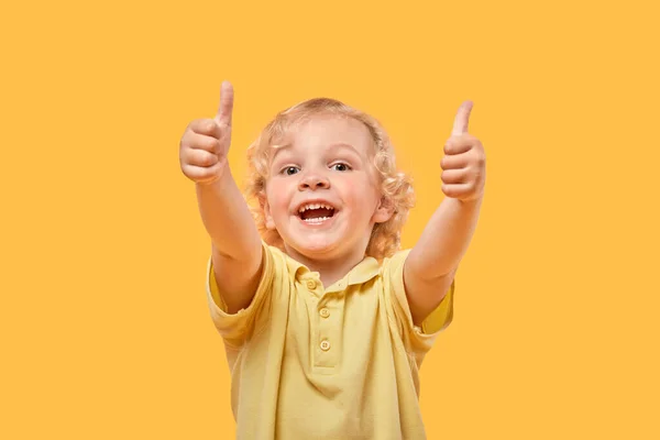 Porträt eines fröhlichen Jungen lockige Blondine zeigt eine super Geste, Daumen hoch. — Stockfoto