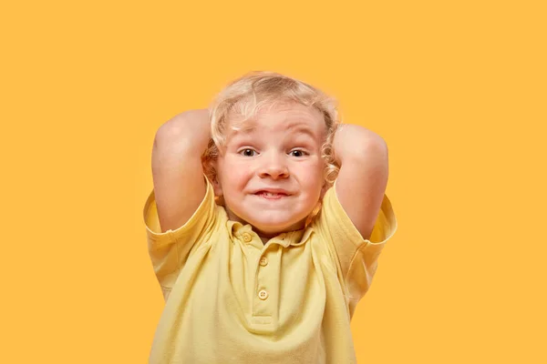Porträt eines schönen fröhlichen Jungen lockig blond auf gelbem Hintergrund. — Stockfoto