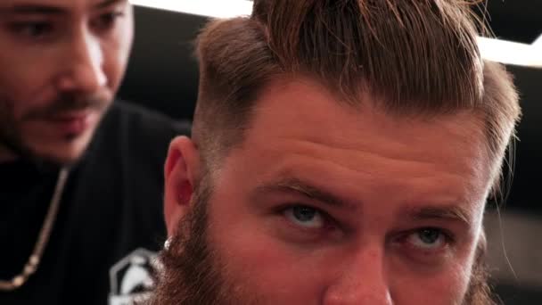 O olhar de um belo homem confiante olha em frente, visitando uma barbearia. — Vídeo de Stock