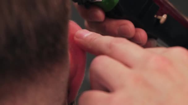 Holič pracuje s nůžkami na vlasy kolem uší. Pánský sestřih v holičství. — Stock video