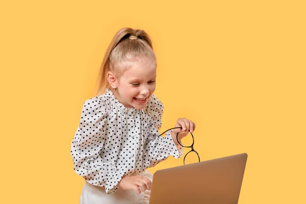 Uma menina assiste a um desenho animado online usando um laptop. — Fotografia de Stock