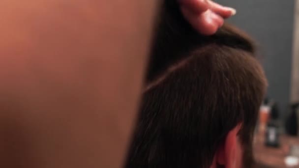 Перукар зачісає довге волосся клієнта в перукарні.. — стокове відео