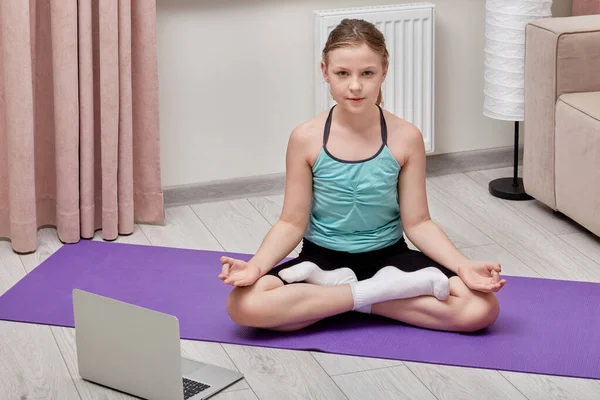 Дівчина робить йогу онлайн вдома, використовуючи ноутбук і навчальний урок . — стокове фото