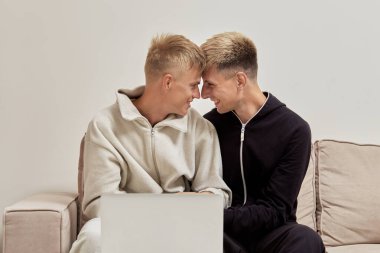 Pijamalı iki adam kanepede birbirine sarılıyor..