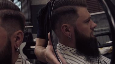 Berber adam elinde bir ayna tutuyor ve sonucu müşteriye gösteriyor..