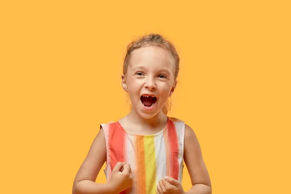Zahnloses glückliches Mädchen mit offenem Mund. Orangefarbener Hintergrund. — Stockfoto