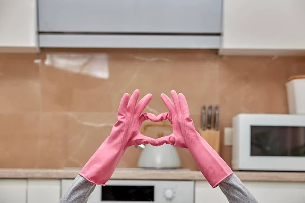 Las manos en guantes de látex se pliegan en forma de corazón en una cocina moderna. — Foto de Stock