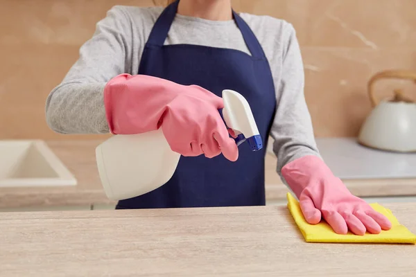 Uma mulher em luvas de borracha aplica detergente de um spray na cozinha. — Fotografia de Stock