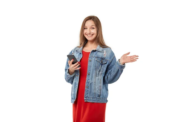 Een jonge blonde vrouw glimlacht, houdt een mobiele telefoon in haar hand. — Stockfoto