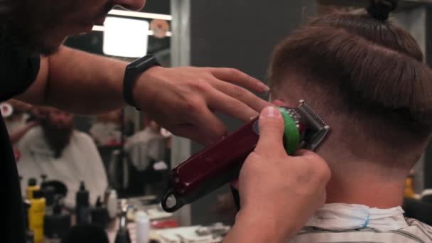 Barber cuts a mans hair with a clipper. Stylish beard and hairstyle. — Stock Video