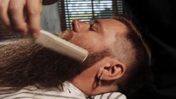 Barber peina la barba larga de los clientes con un peine pequeño. Corte de barba de moda. — Vídeos de Stock